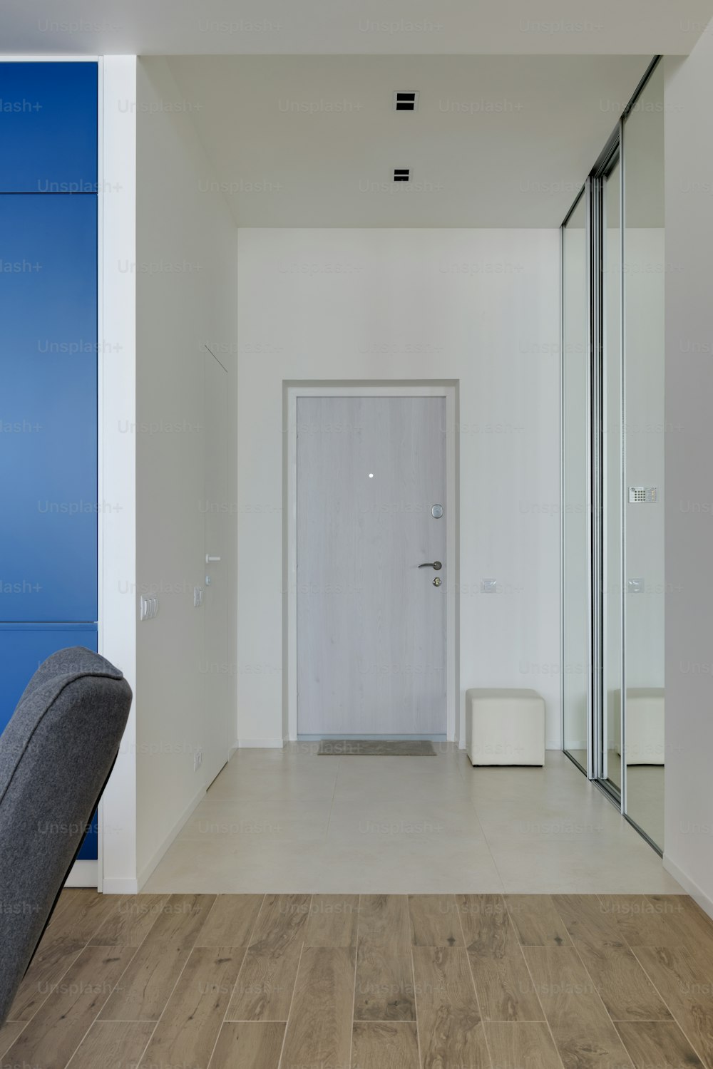 a white room with a gray chair and a white door