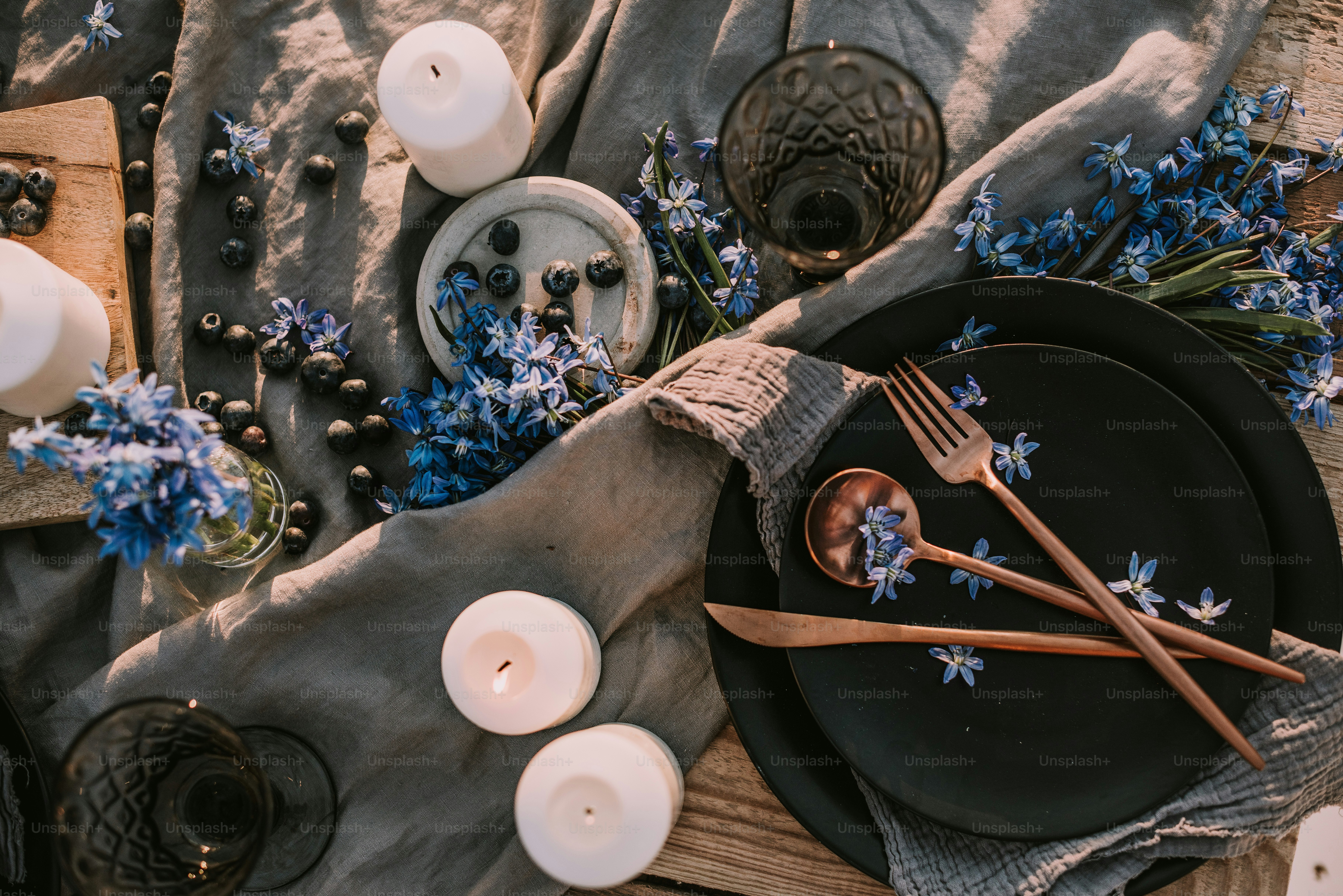 A table topped with lots of white and blue flowers photo – Candles ...