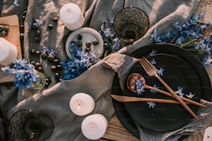 a table setting with blue flowers and candles