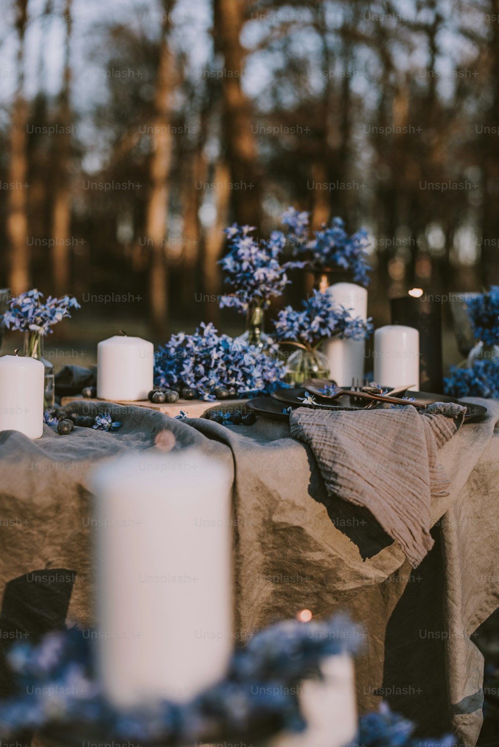 a table topped with white candles and blue flowers