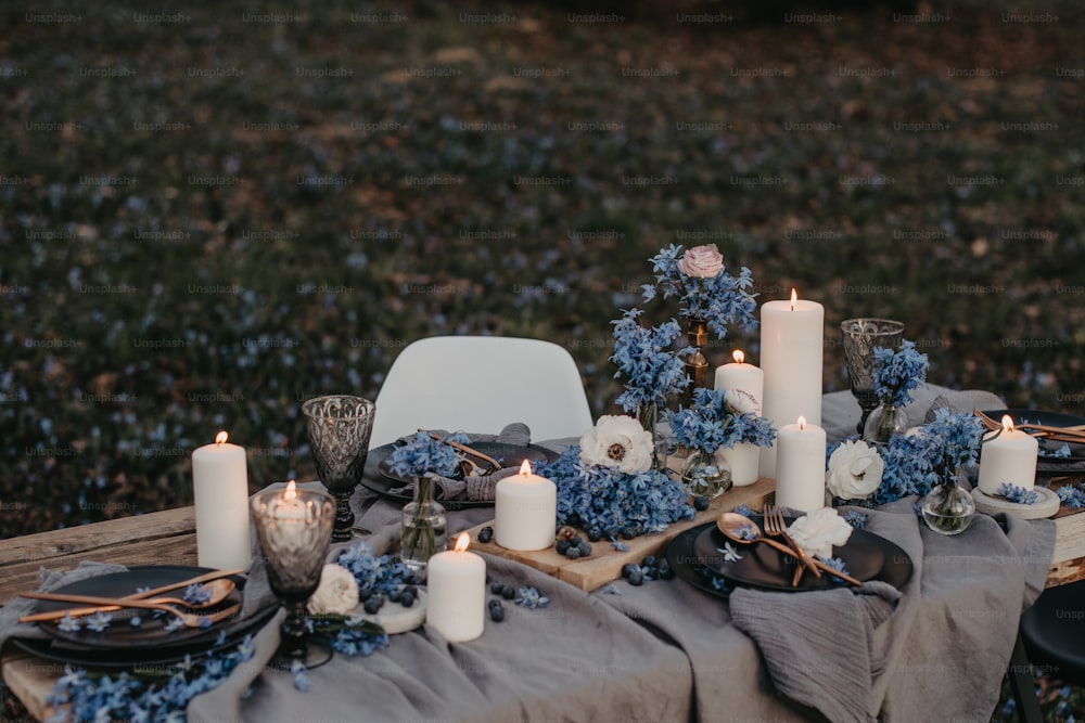 a table topped with plates and candles next to a field