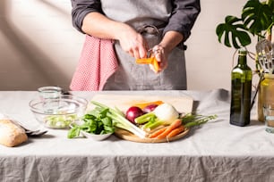 Una persona parada frente a una tabla de cortar con verduras