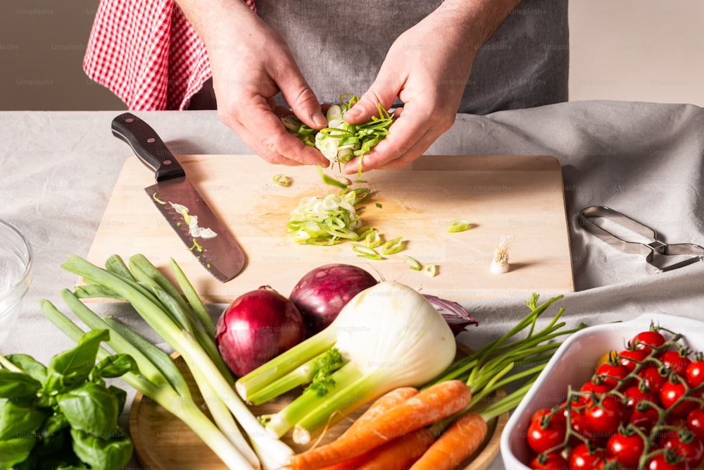 a person cutting up vegetables on a cutting board