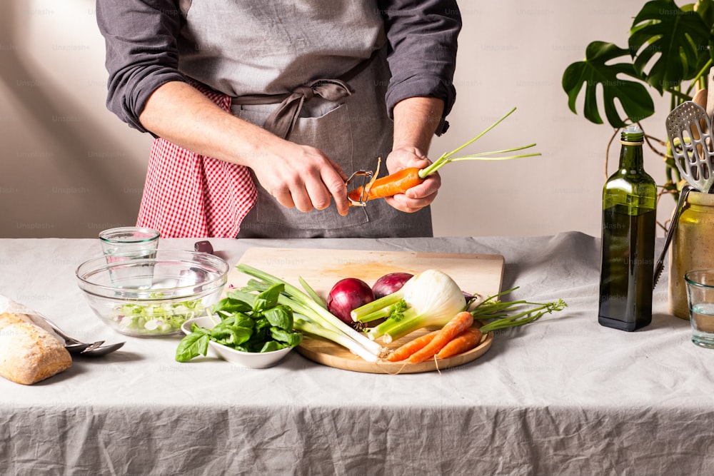 Una persona en un delantal preparando verduras en una mesa