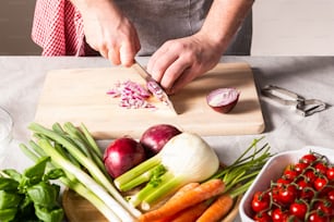 a person cutting up vegetables on a cutting board