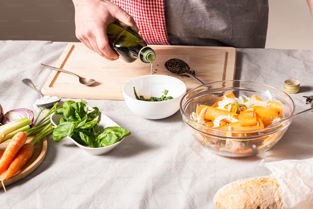 a person pouring a bottle of wine into a bowl of vegetables