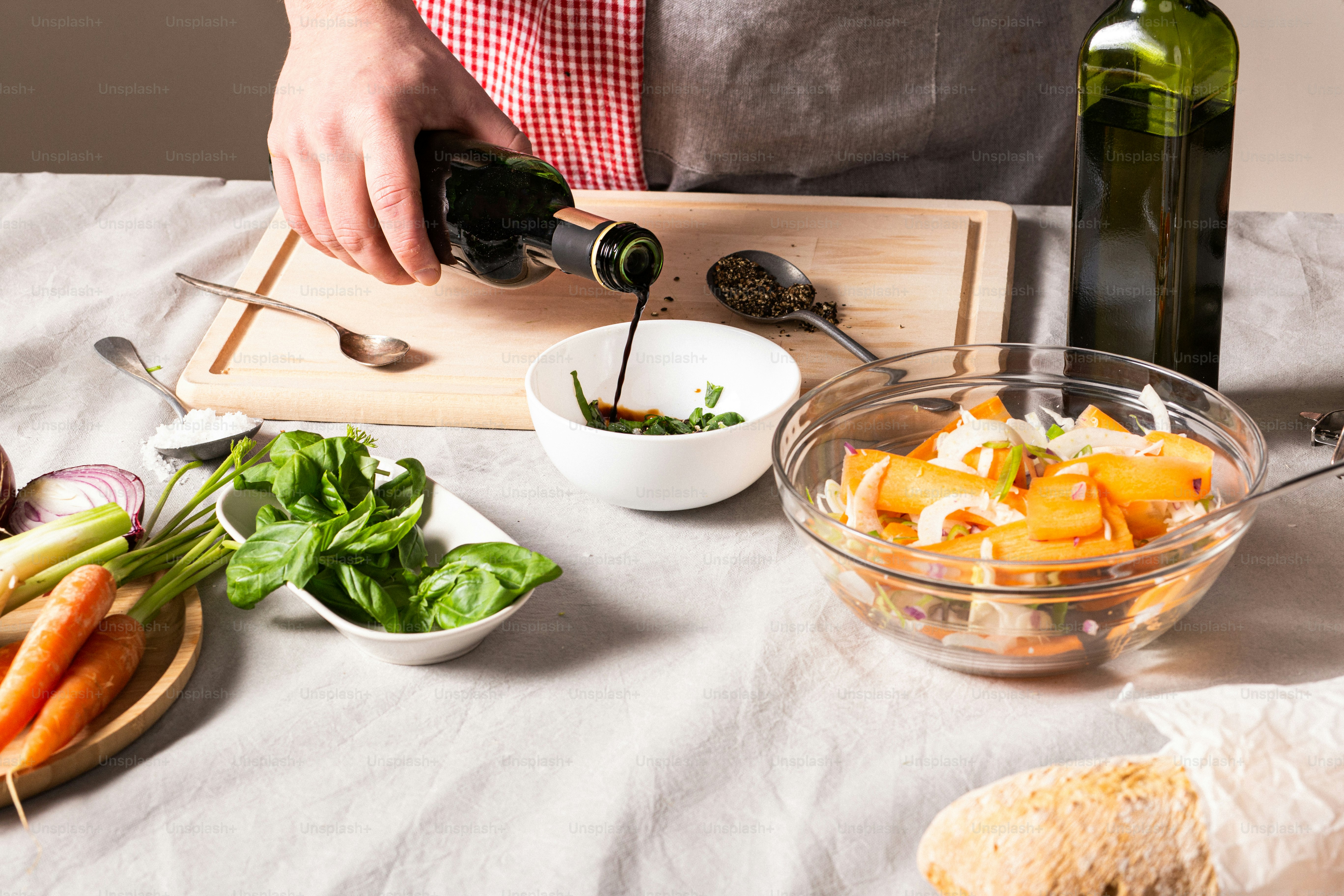 a person pouring a bottle of wine into a bowl of vegetables