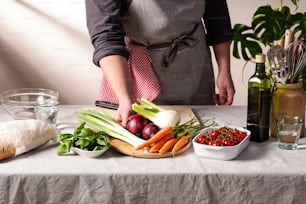 a person in an apron cutting vegetables on a table