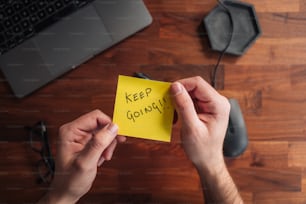 a person holding a sticky note with the words keep going written on it