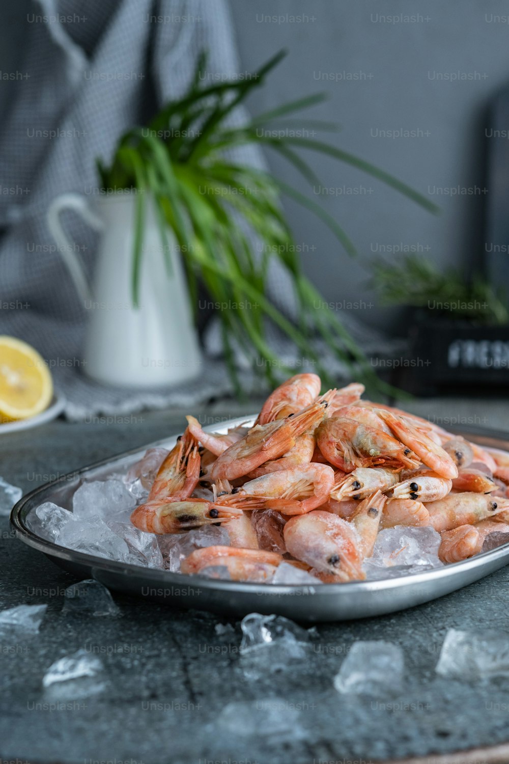 a plate of shrimp on ice with lemon wedges