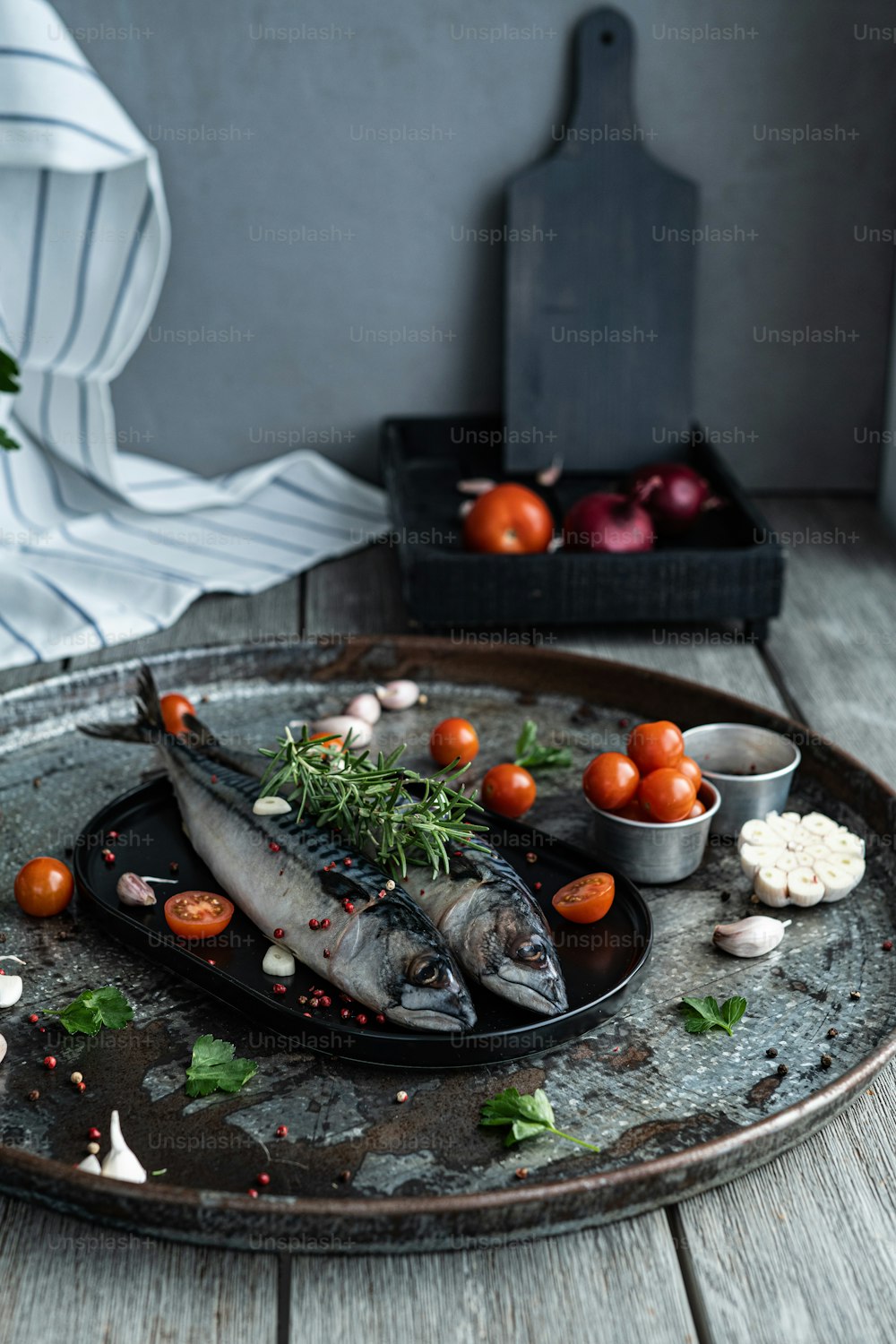 um prato com alguns peixes e tomates sobre ele