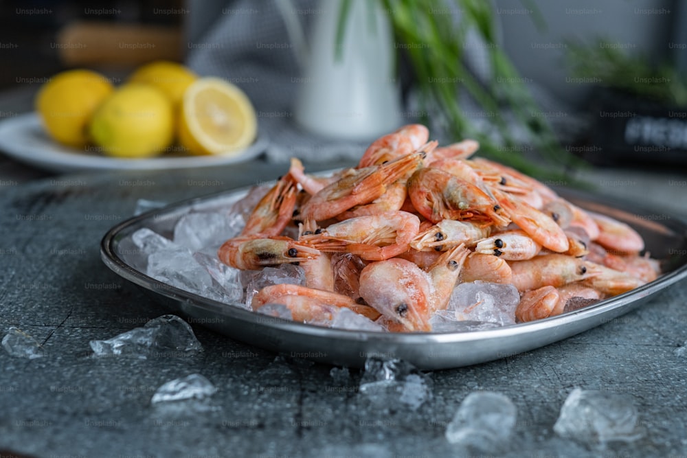 a plate of shrimp on ice with lemons in the background