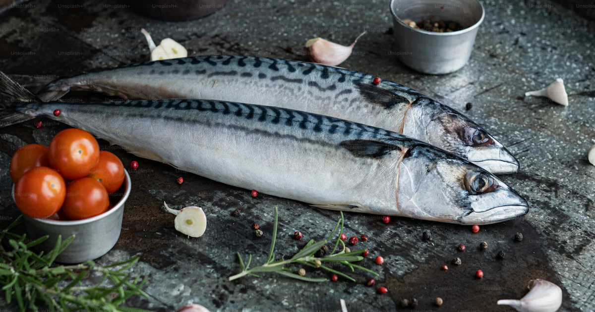 A couple of fish sitting on top of a metal tray photo – Raw fish Image ...