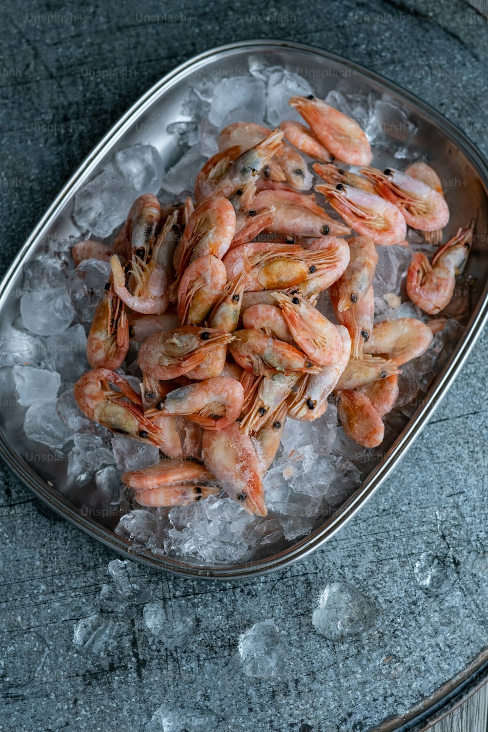 a metal bowl filled with shrimp on top of ice