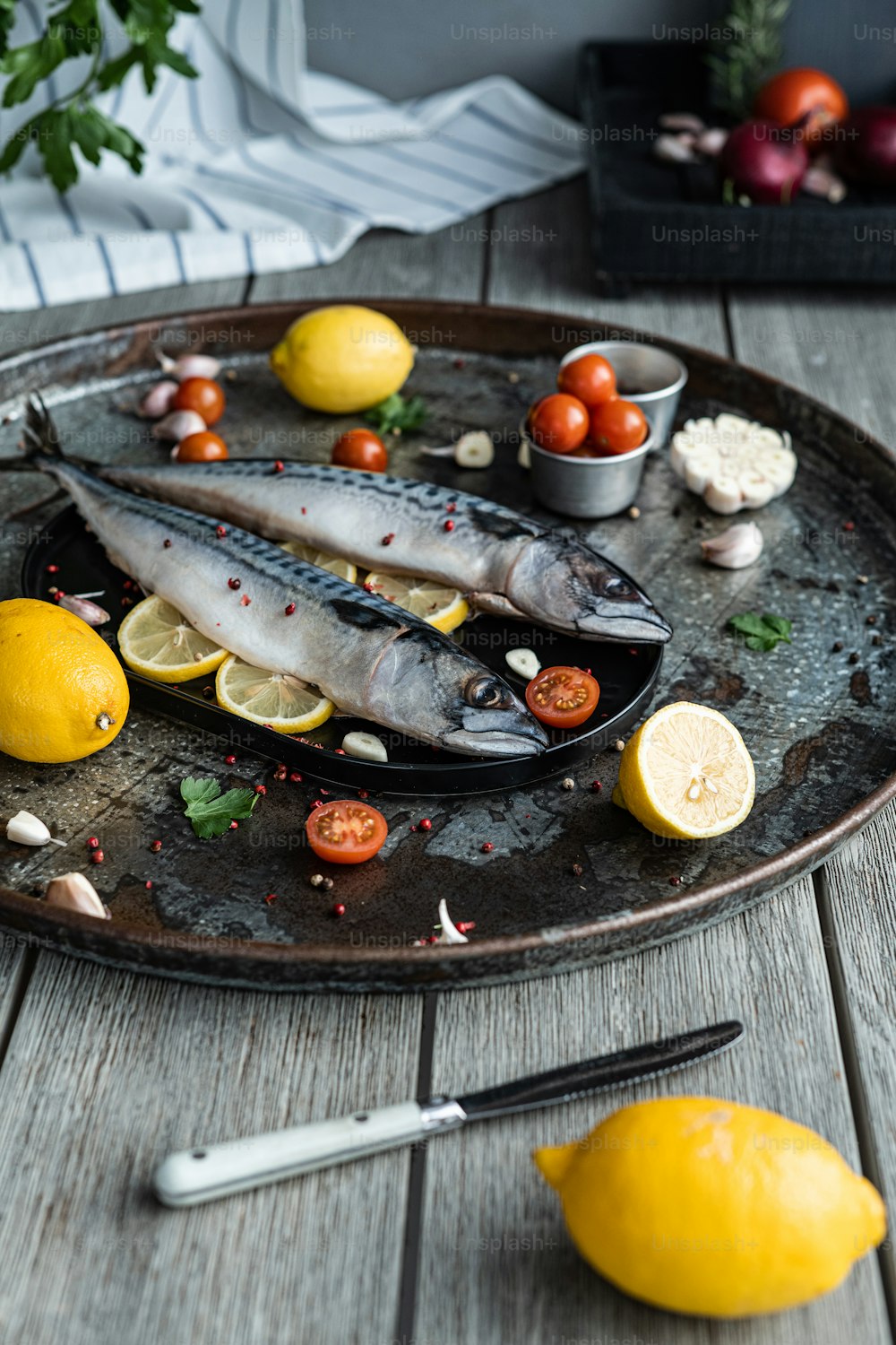 Un plato de pescado con limones, tomates y ajo