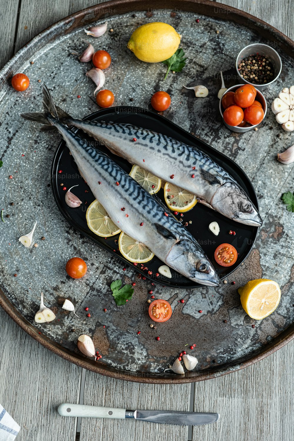 Dos peces están en un plato con limones y tomates