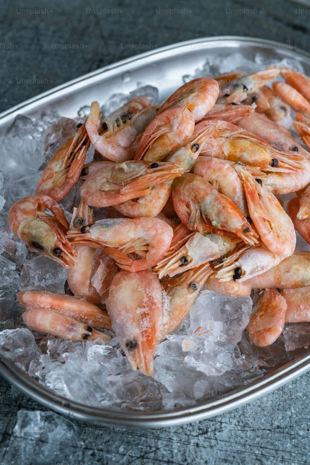 a metal bowl filled with shrimp on top of ice