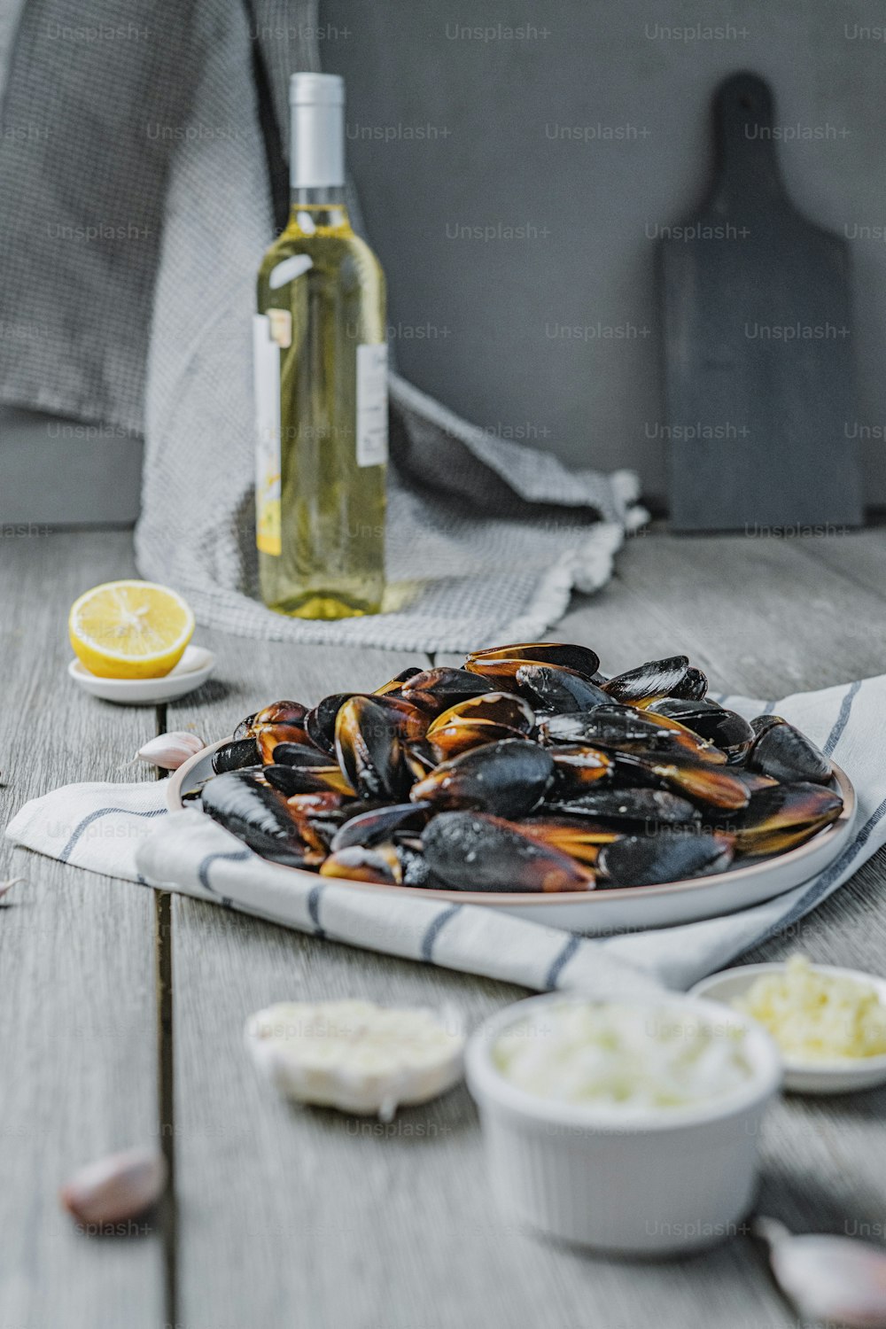 a plate of mussels on a table with a bottle of wine
