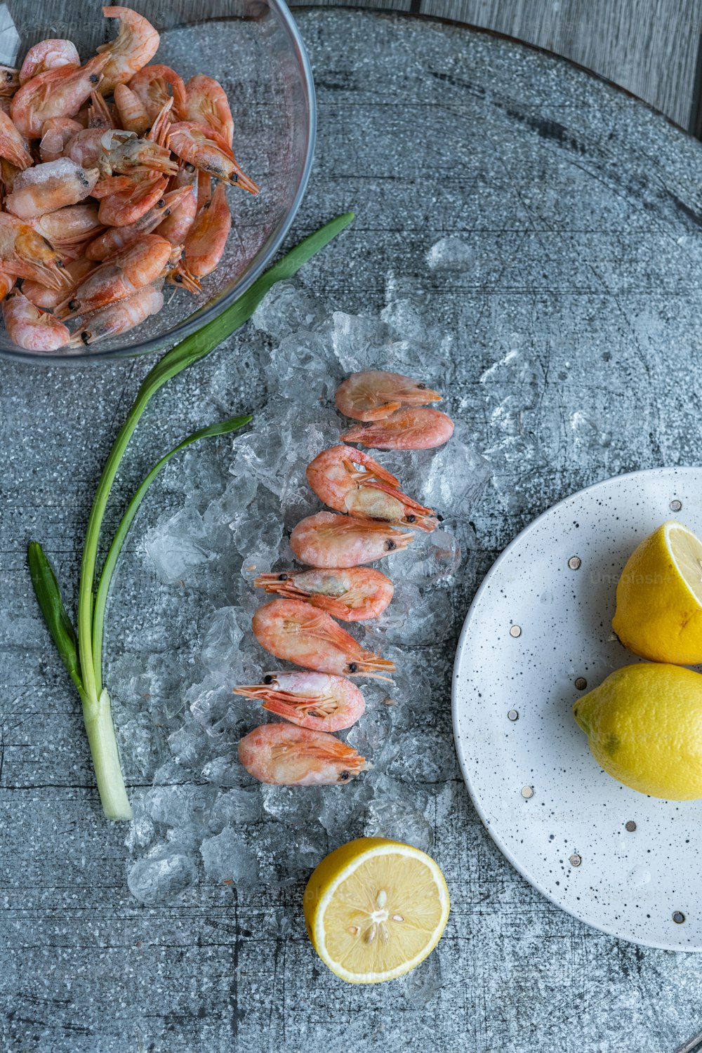 a plate of shrimp next to a bowl of lemons