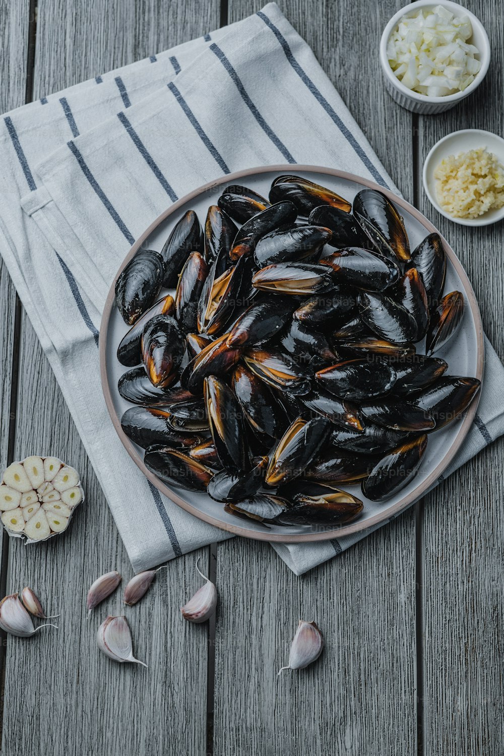 Une assiette pleine de moules sur une table en bois