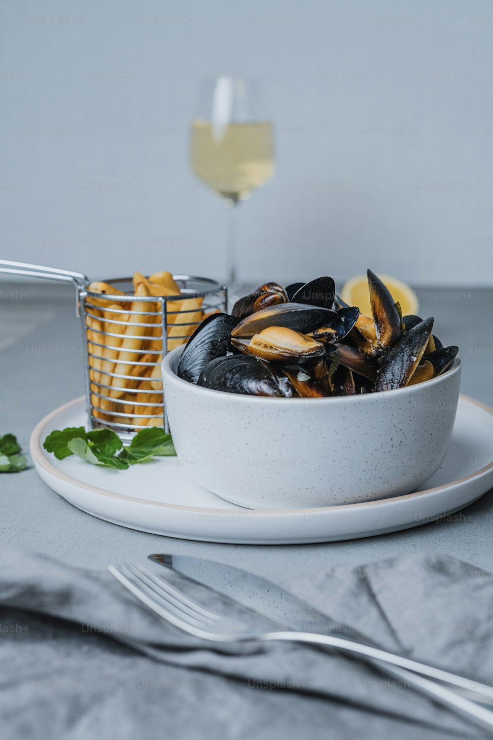 a white bowl filled with mussels next to a glass of wine