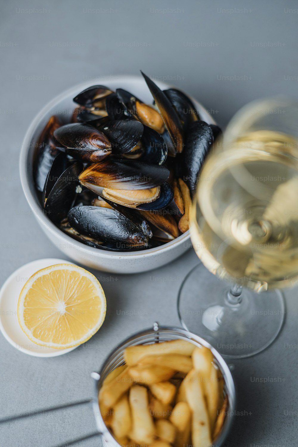 a bowl of mussels next to a glass of wine