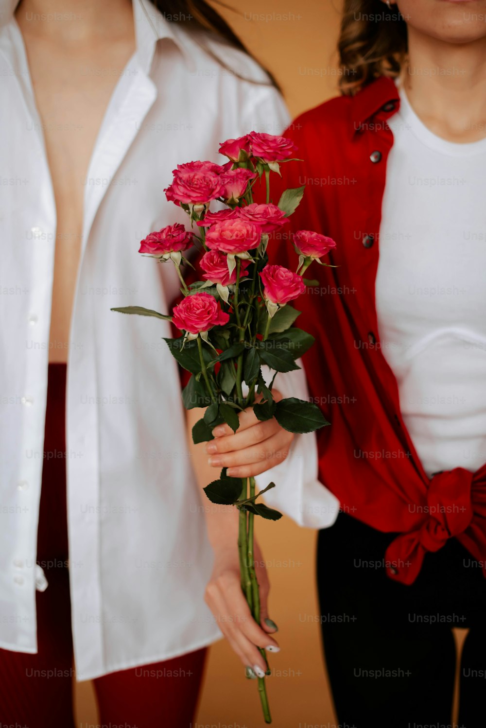 別の女性の隣にバラの花束を持つ女性