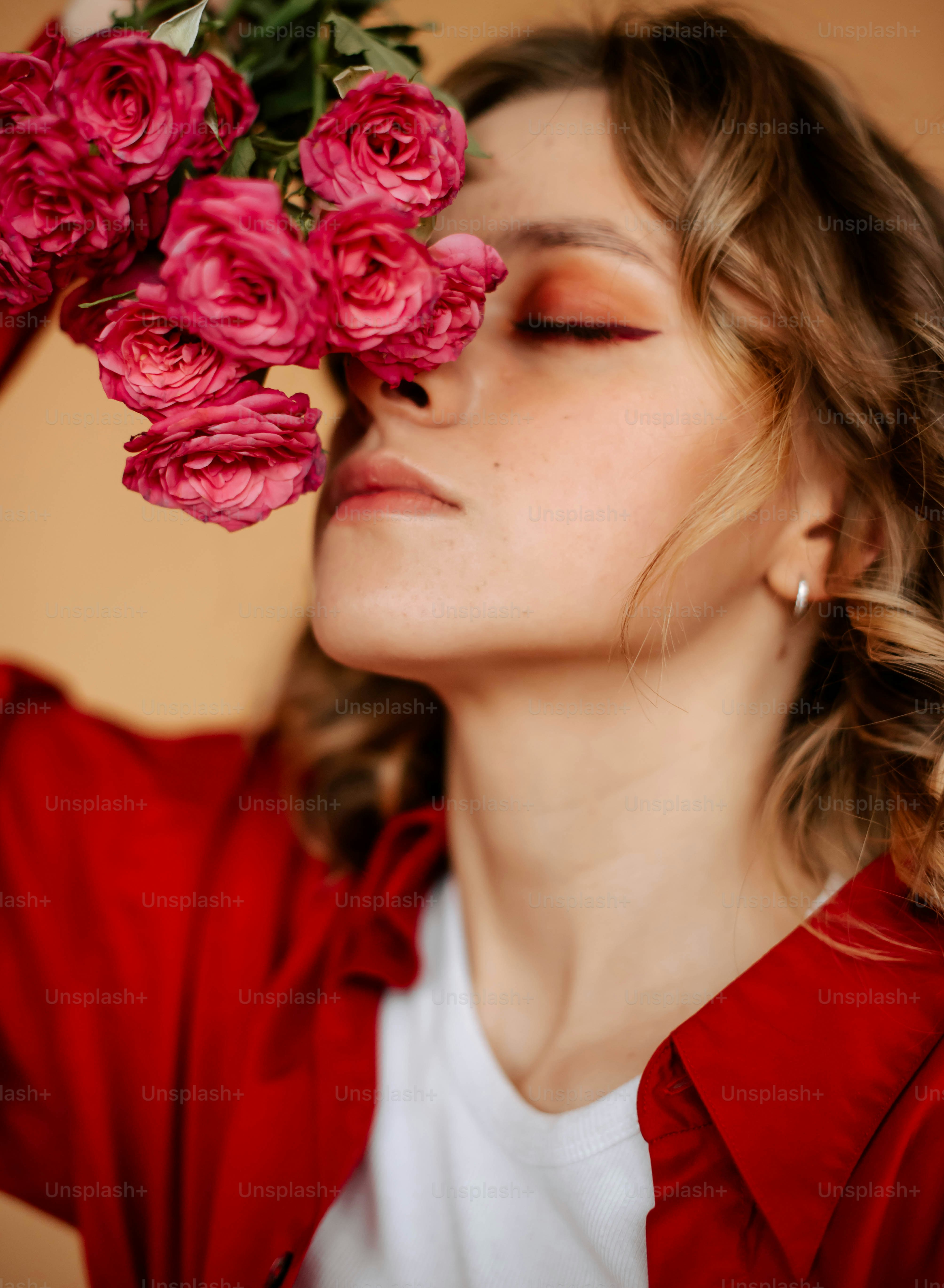 Una mujer sosteniendo un ramo de flores rosadas sobre su cara