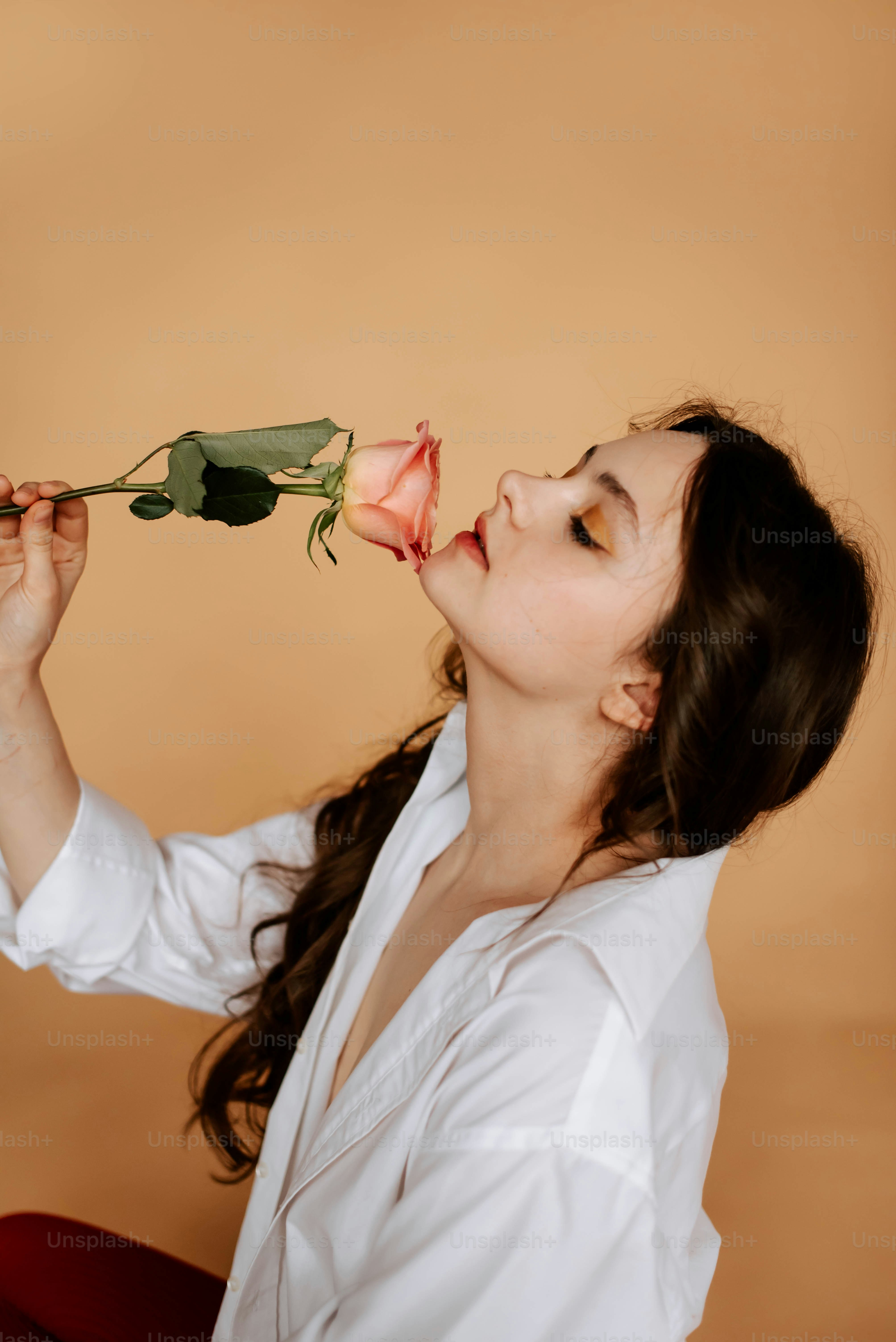a woman holding a rose up to her face