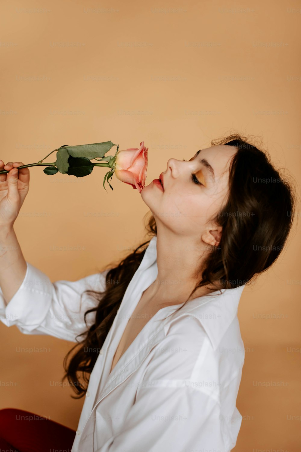 uma mulher segurando uma rosa até o rosto