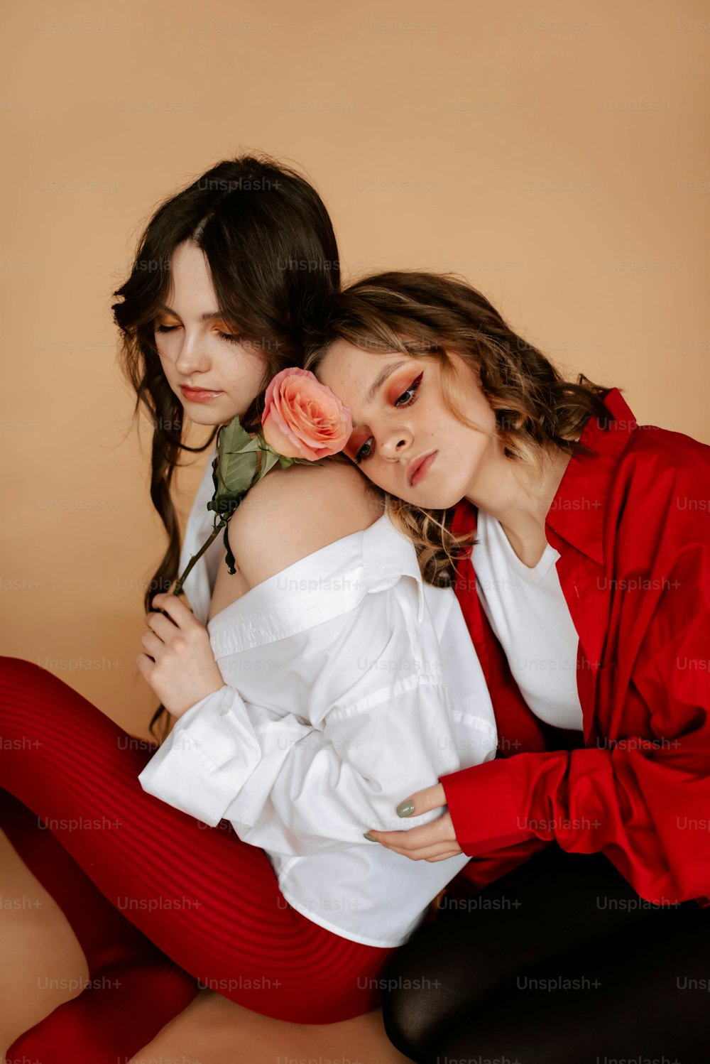 Zwei Frauen sitzen auf dem Boden, eine hält eine Rose in der Hand