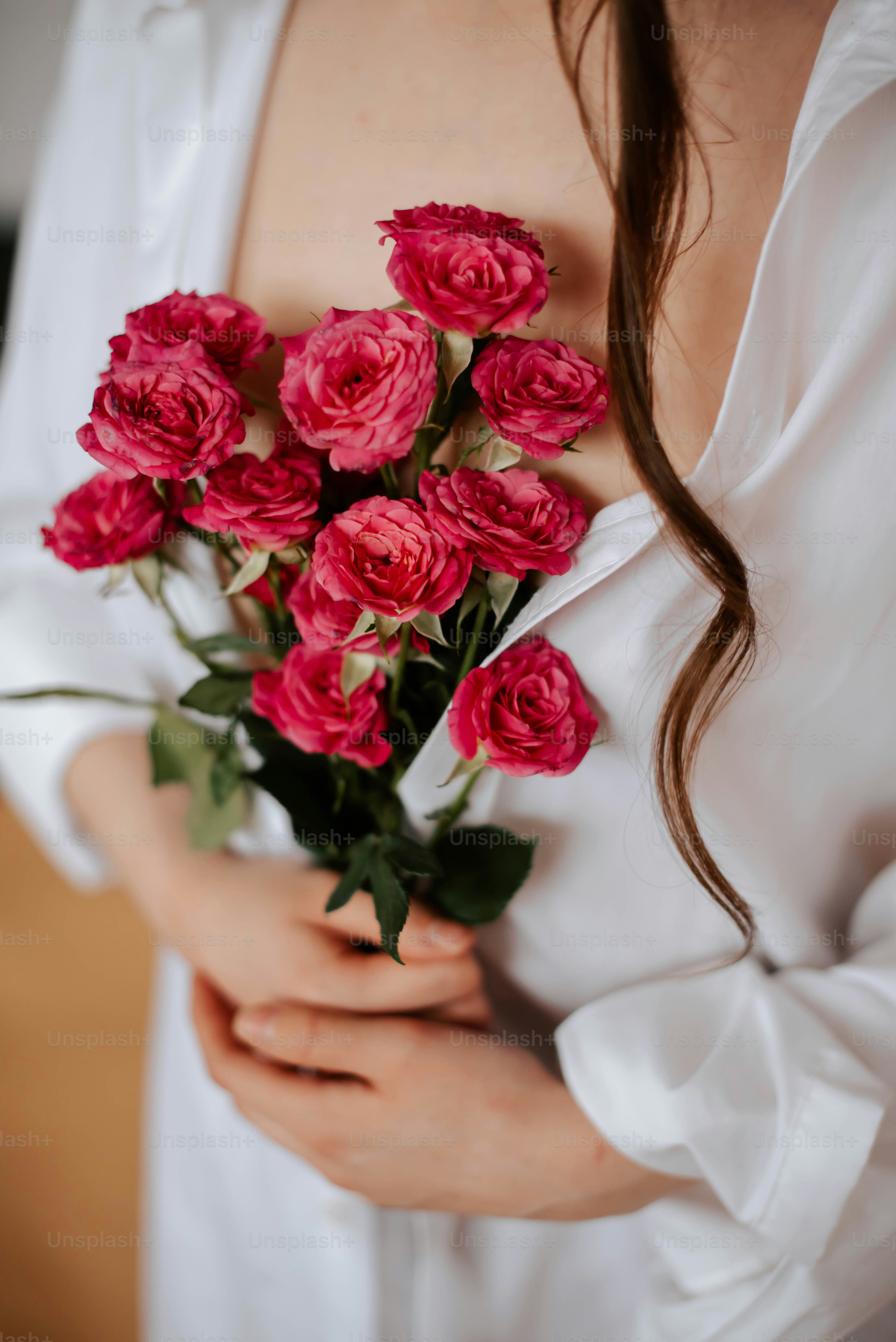a woman holding a bouquet of pink roses