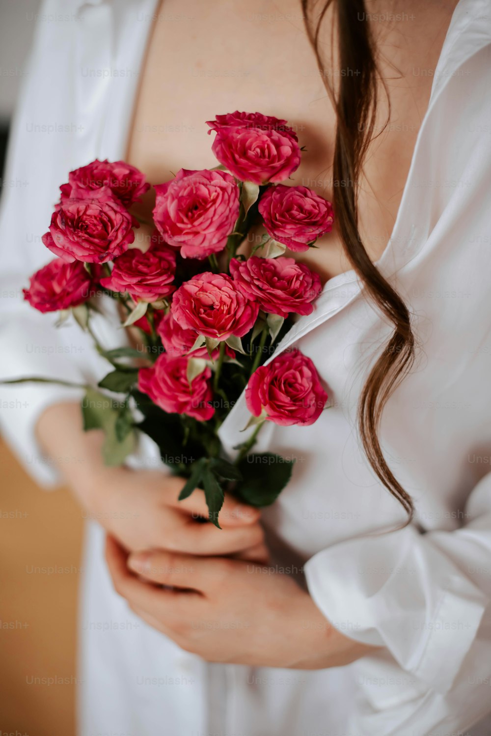 a woman holding a bouquet of pink roses