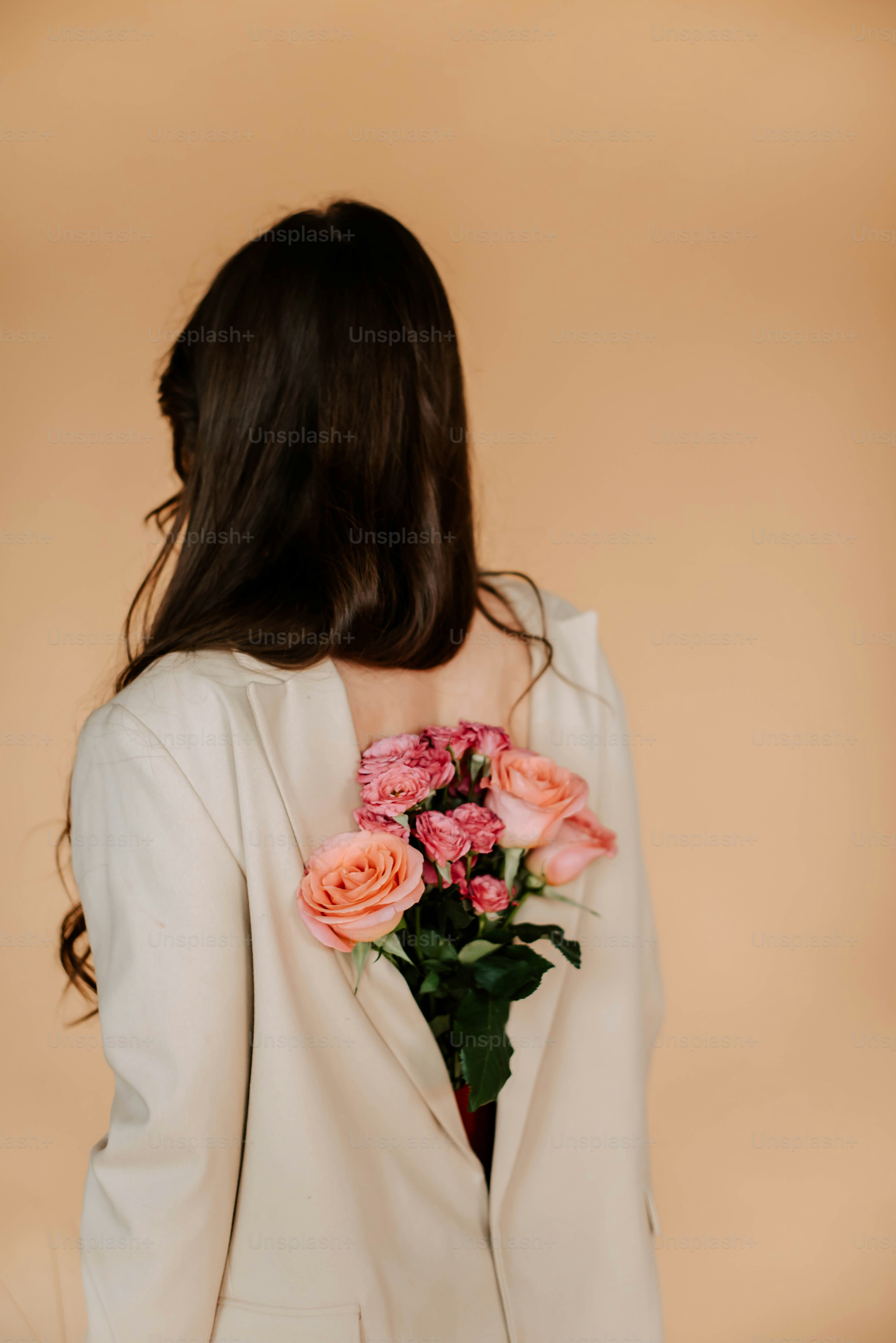 una donna in un abito bianco che tiene un mazzo di fiori