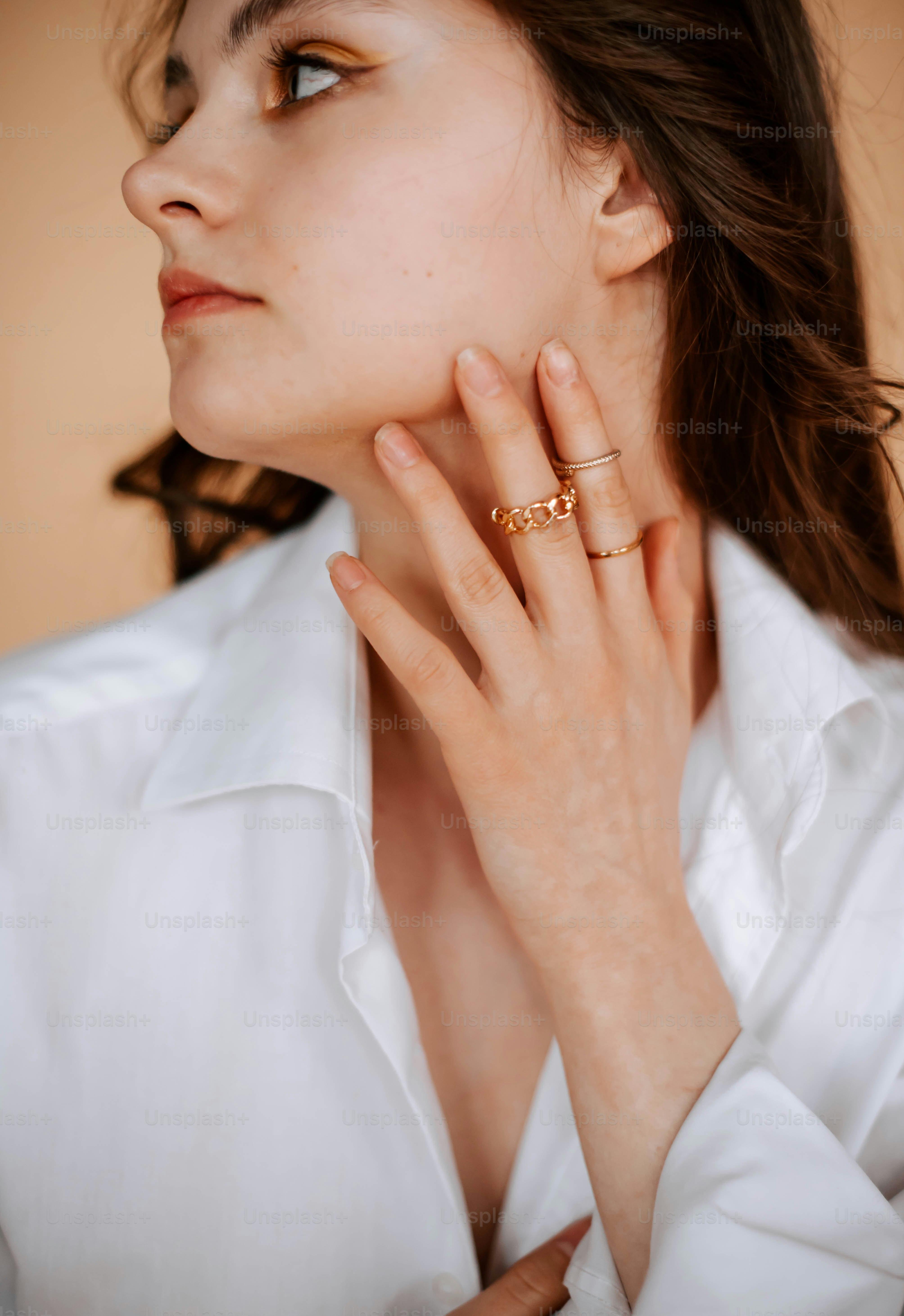 a woman wearing a white shirt and a gold ring