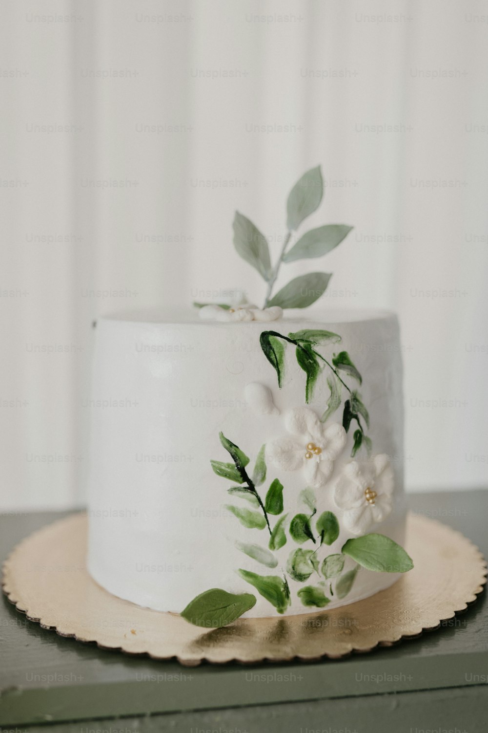 un pastel blanco con flores y hojas en la parte superior
