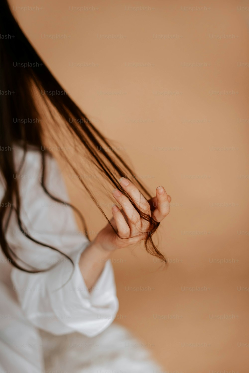 a woman in a white shirt is holding her hair