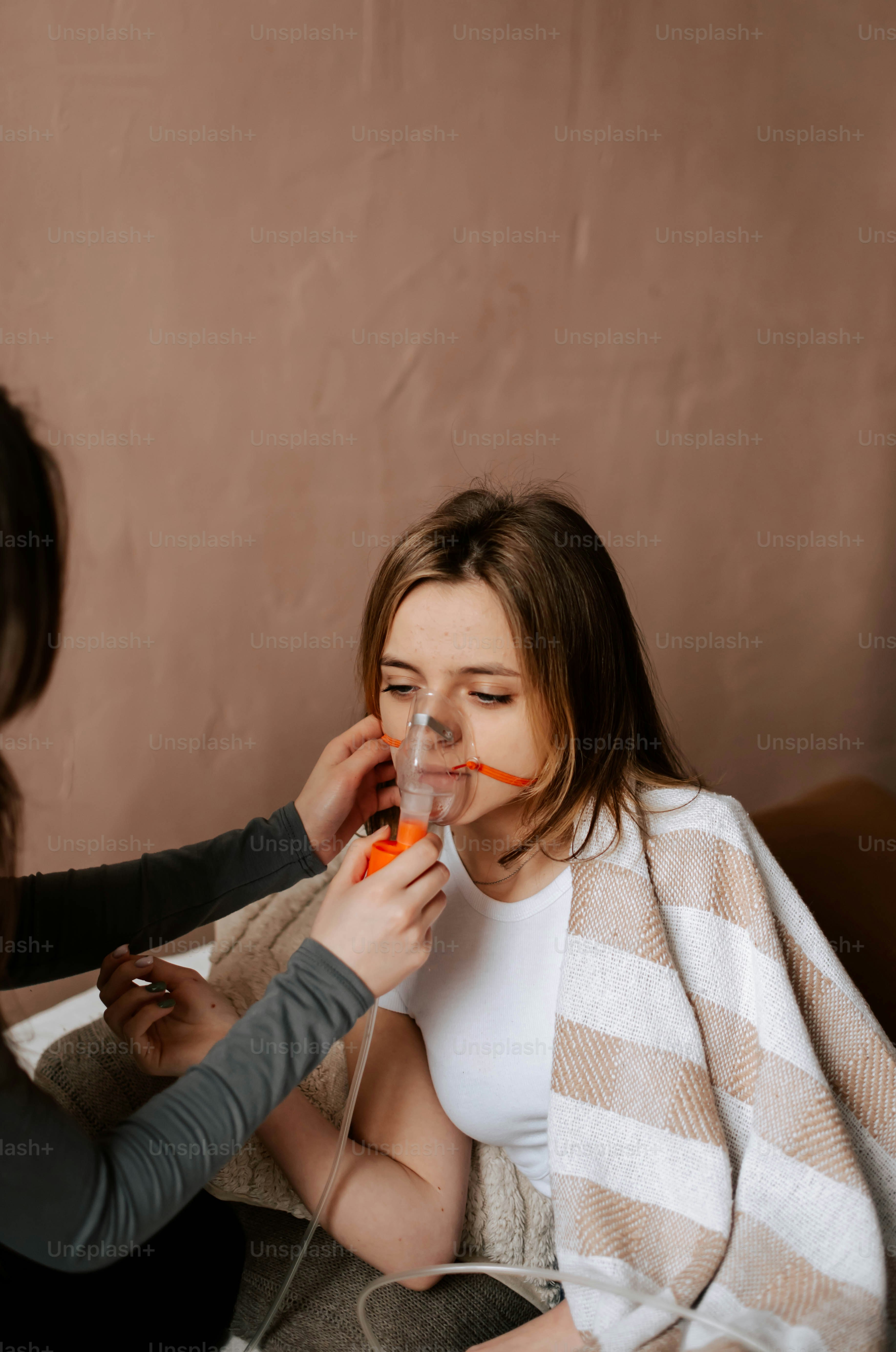two women sitting on a couch one of them is holding an orange object