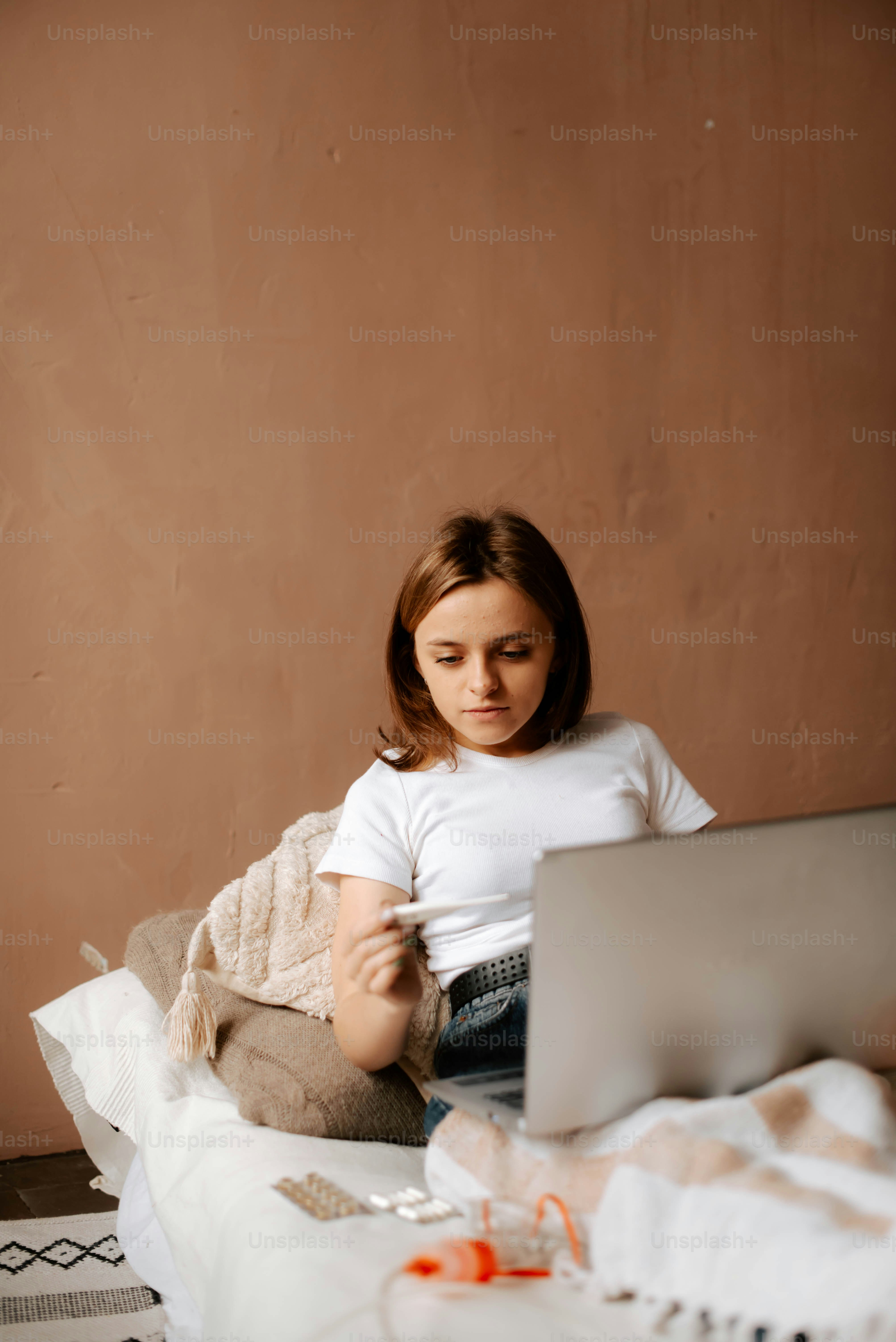 a young girl sitting on a bed using a laptop computer