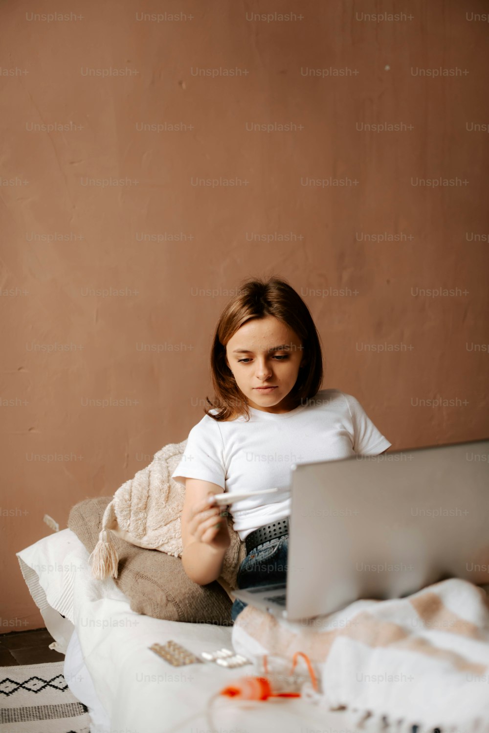Ein junges Mädchen, das mit einem Laptop auf einem Bett sitzt