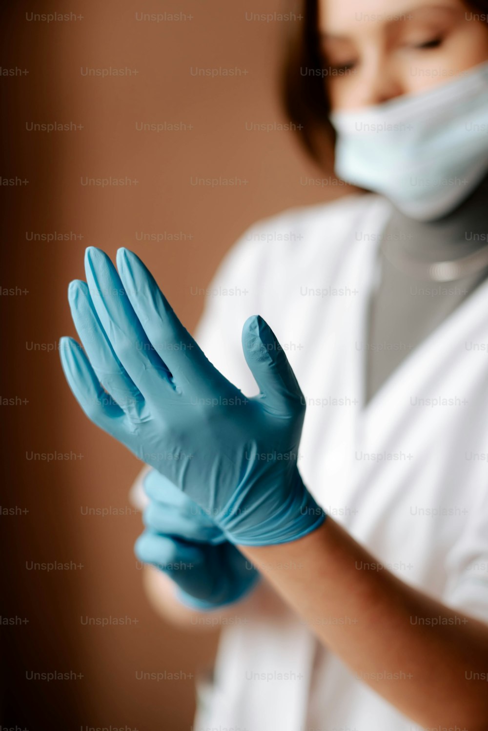 a woman wearing blue gloves and a face mask