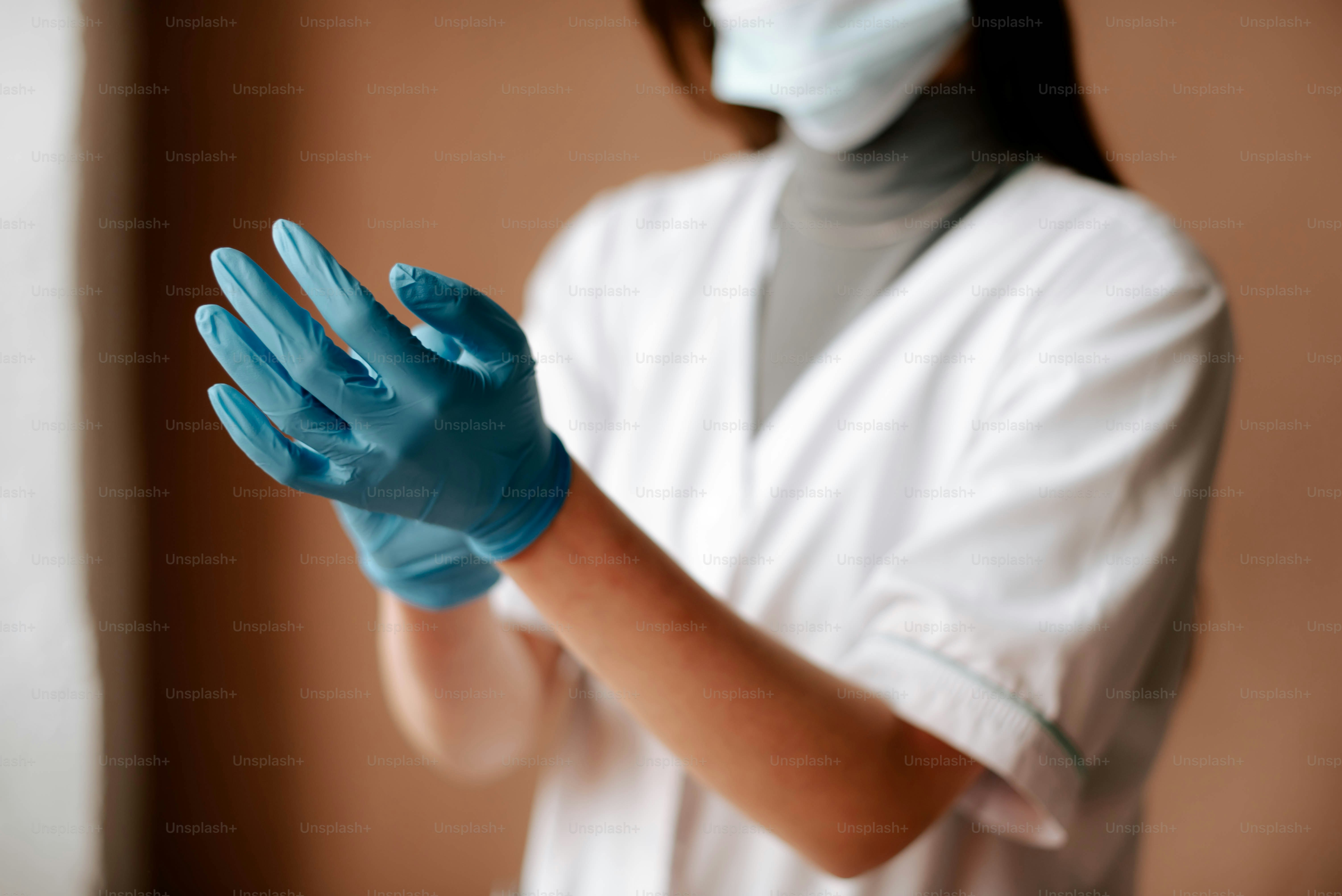 une femme portant un masque chirurgical et des gants bleus