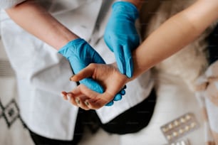 a person in blue gloves holding another person's hand