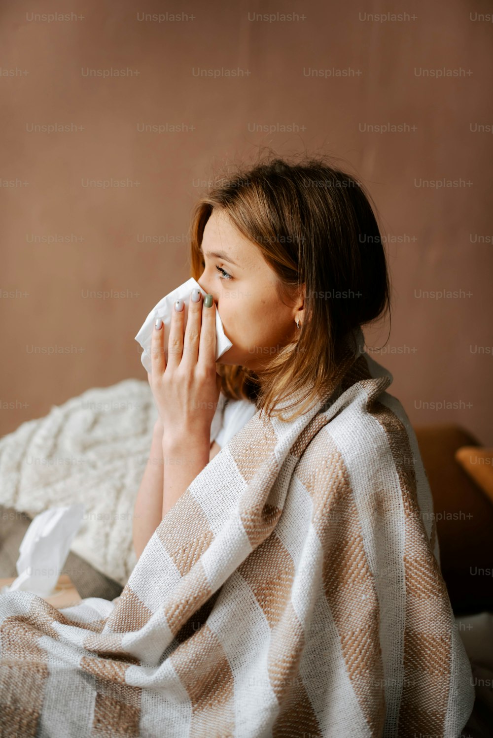 a woman sitting on a bed wrapped in a blanket
