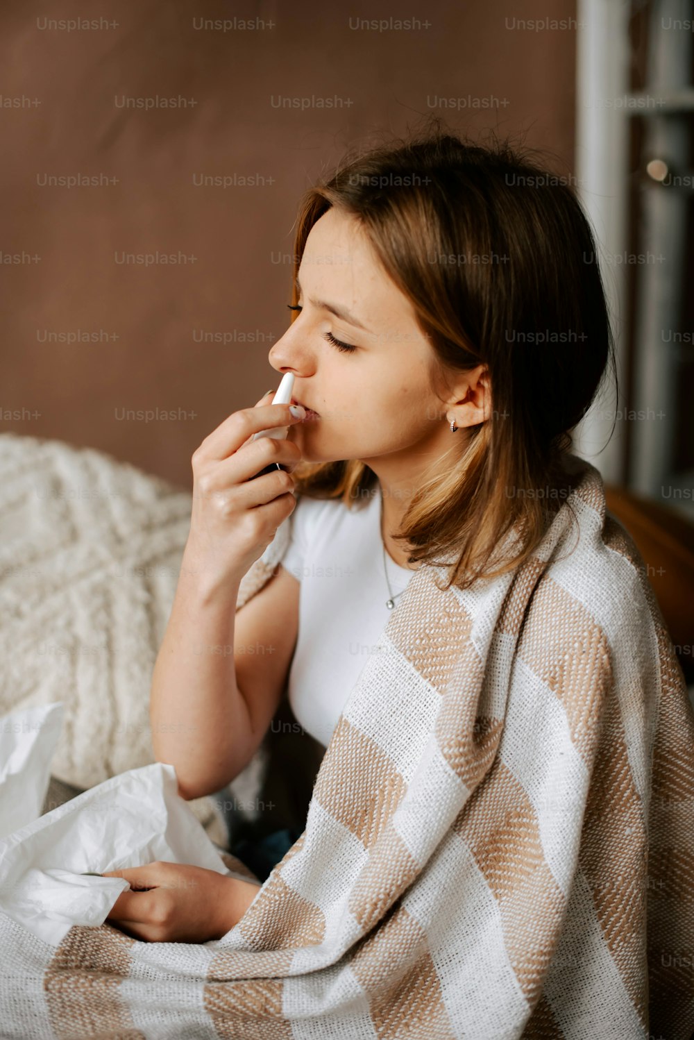 a woman sitting on a bed wrapped in a blanket