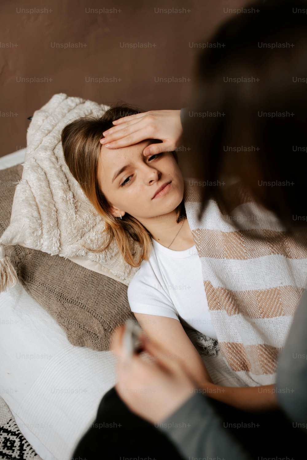 uma mulher sentada em uma cama segurando sua cabeça
