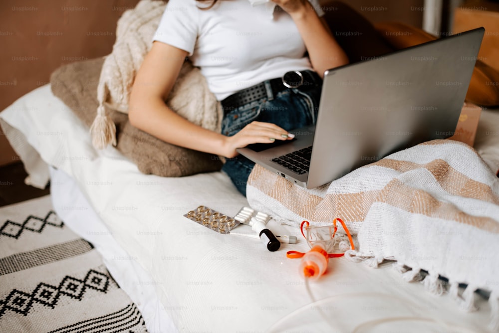 노트북 컴퓨터를 사용하여 침대에 앉아 있는 여자