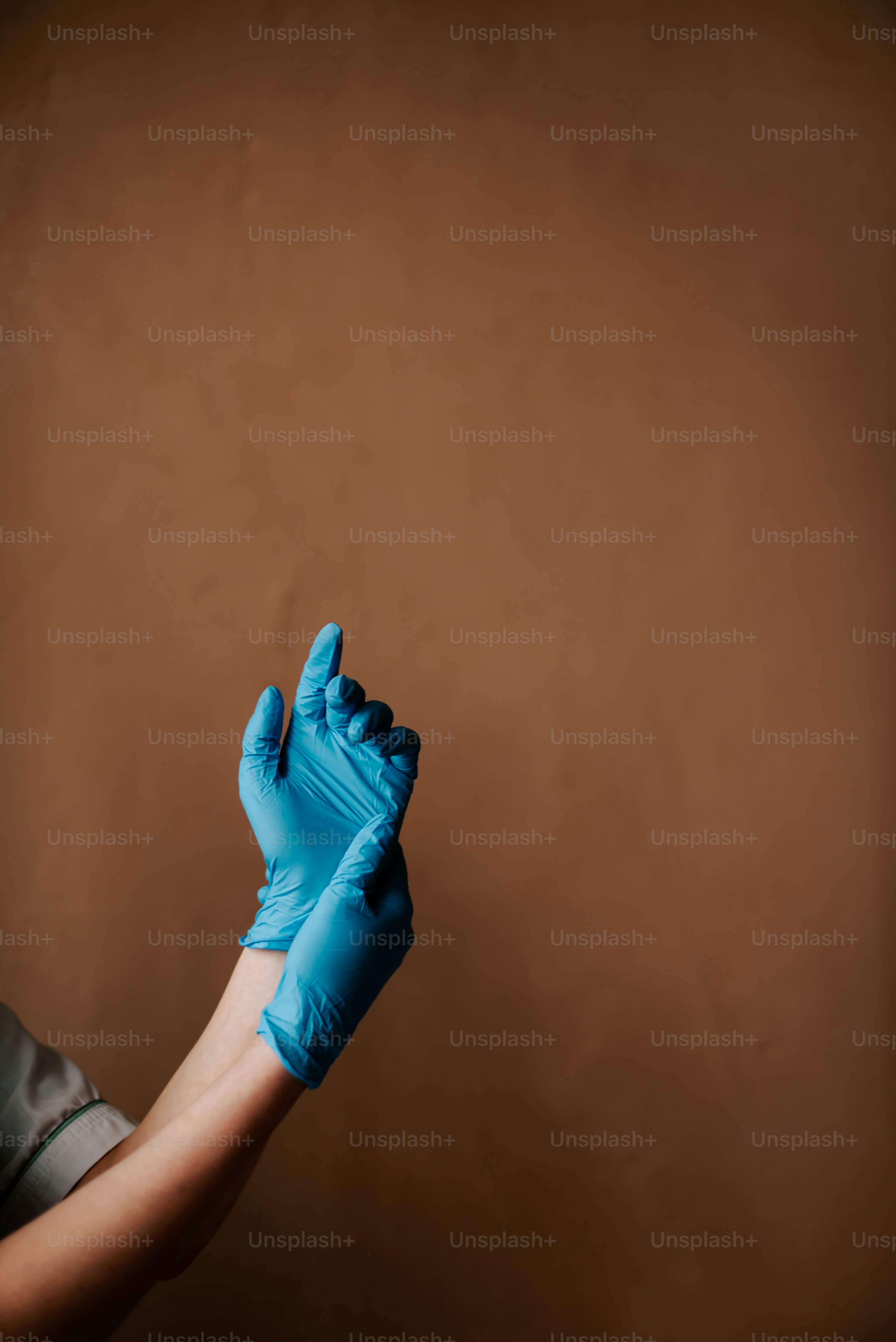 eine Person, die blaue Handschuhe trägt und ein Mobiltelefon in der Hand hält