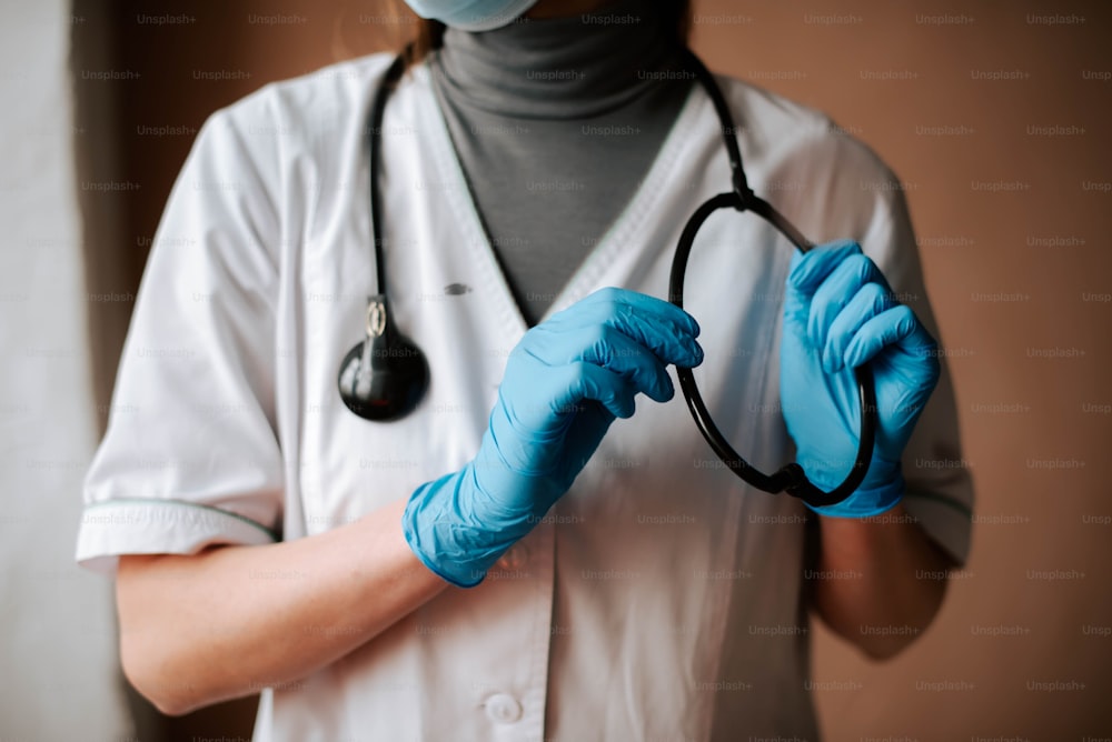 eine Person mit blauen Handschuhen, die ein Stethoskop hält