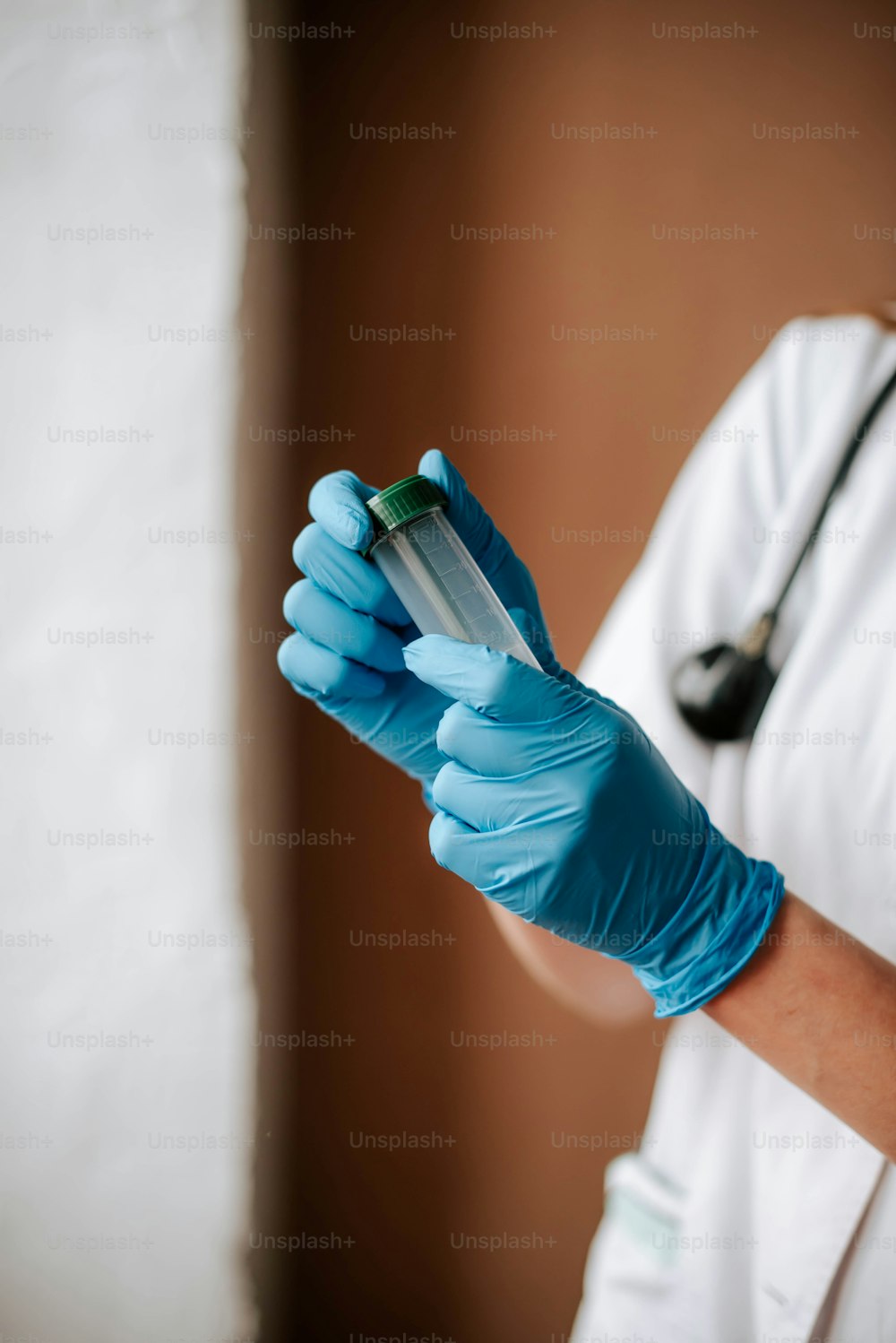 a person in a white coat and blue gloves holding a tube